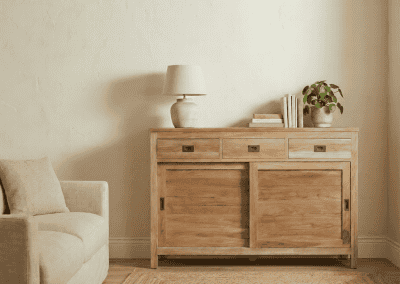 Lichte woonkamer met teak dressoir Bumi 150 cm, lamp en beige fauteuil op jute vloerkleed.