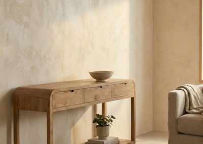 Woonkamer met beige muur en vloerkleed, teak wandtafel Arus met drie lades en plank, decoratieve kom, vaas met plant en boeken, beige bank.