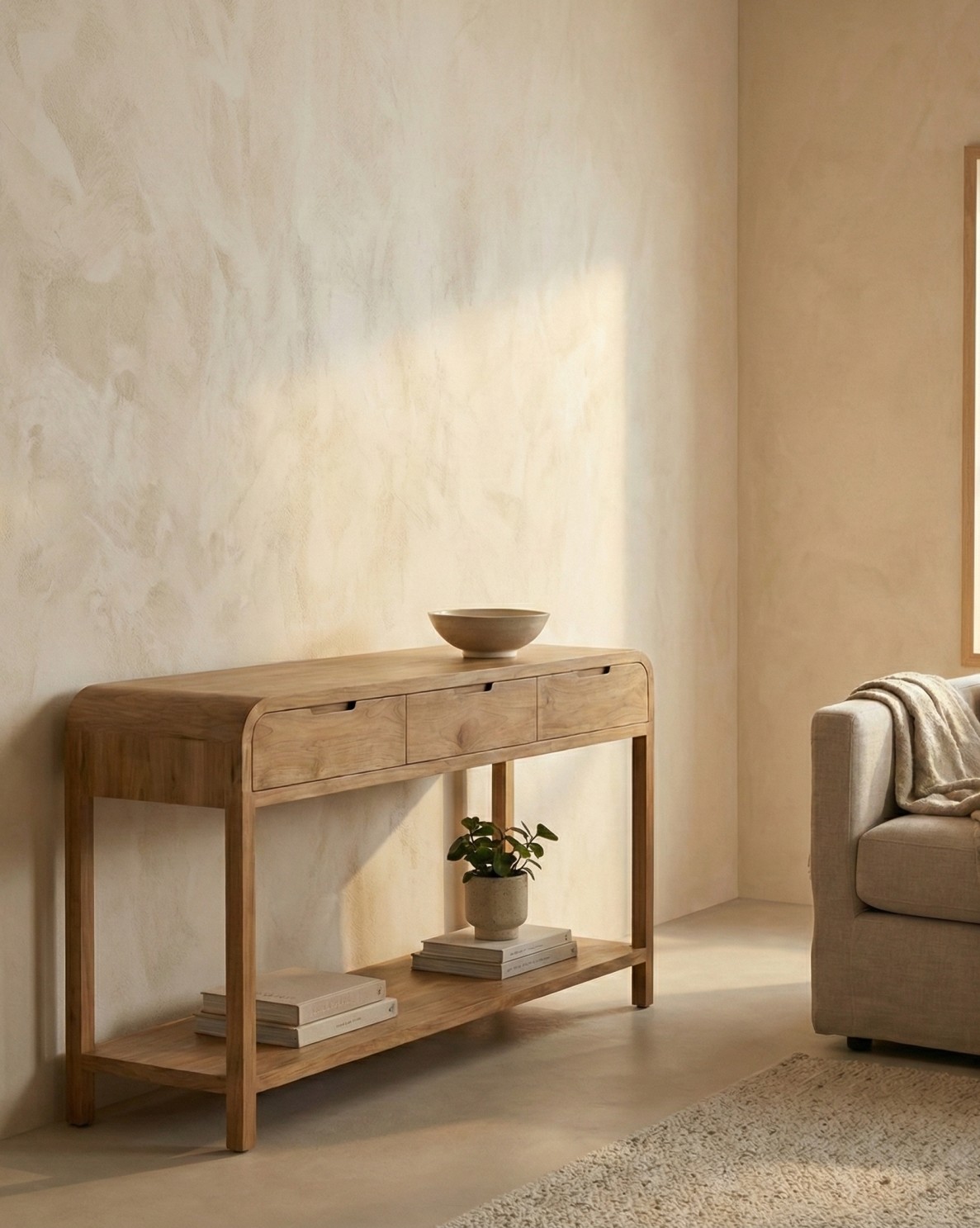 Woonkamer met beige muur en vloerkleed, teak wandtafel Arus met drie lades en plank, decoratieve kom, vaas met plant en boeken, beige bank.